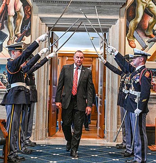 Julie Smith/News Tribune photo: 
Lt. Governor Mike Kehoe enters the Missouri House Lounge under a saber arc Monday, April 22, 2024, at the opening of a ceremony to recognize the 80th anniversary of the World War II battle of the Exercise Tiger. During the ceremony, two World War II veterans were recognized. Organizers also promoted an anniversary celebration Sunday, April 28, at the Navy Anchor Memorial at the Audrain County Courthouse.